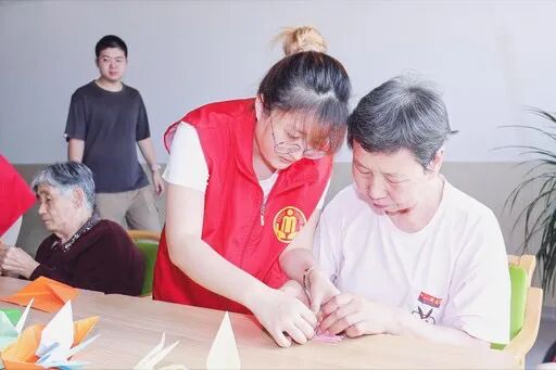 威海市社会福利中心志愿者与老人一起做手工。