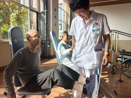 威海市社会福利中心工作人员辅助老人进行康复训练。