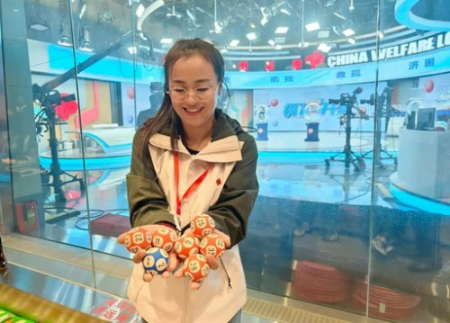 参加“走近双色球”活动的广西福彩观摩团成员——福彩销售站代销者邹利梅触摸“退役”摇奖球。